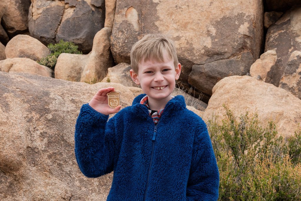 A boy grinning and holding up a badge