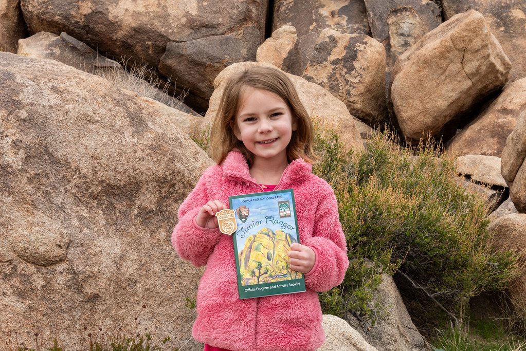 A girl holding up the badge book she just completed