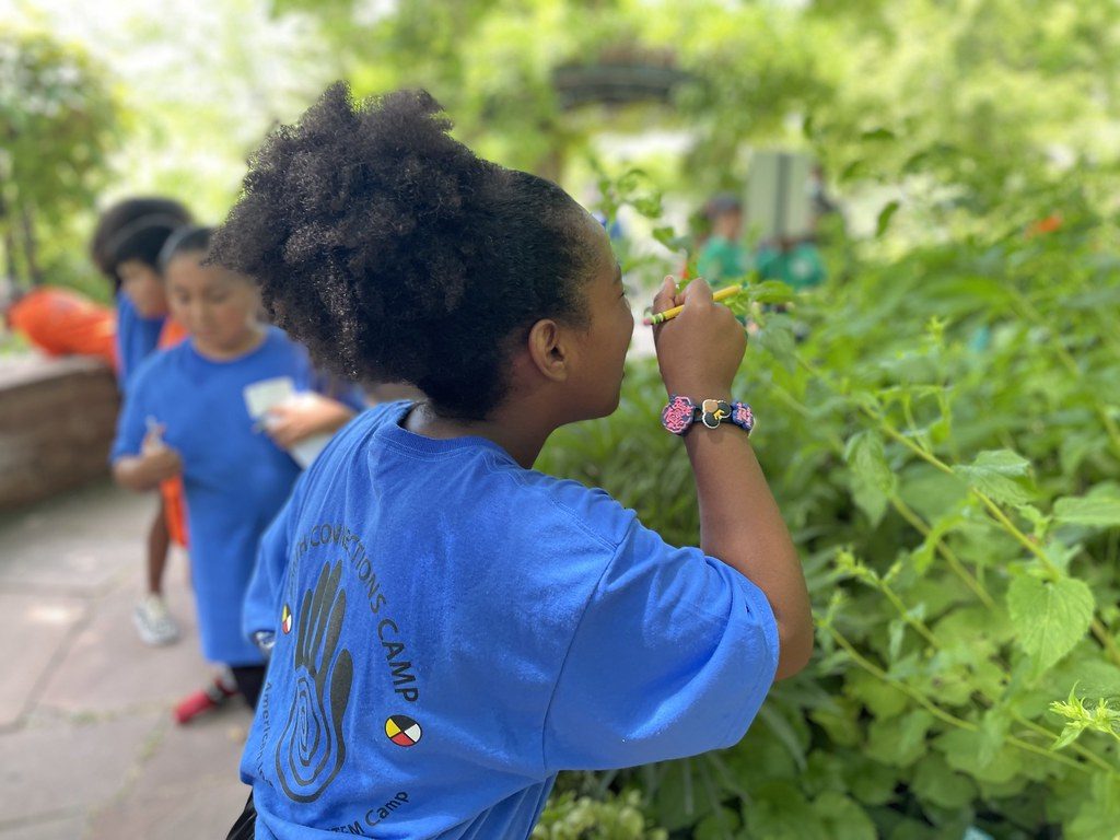 A girl examining a plant up close